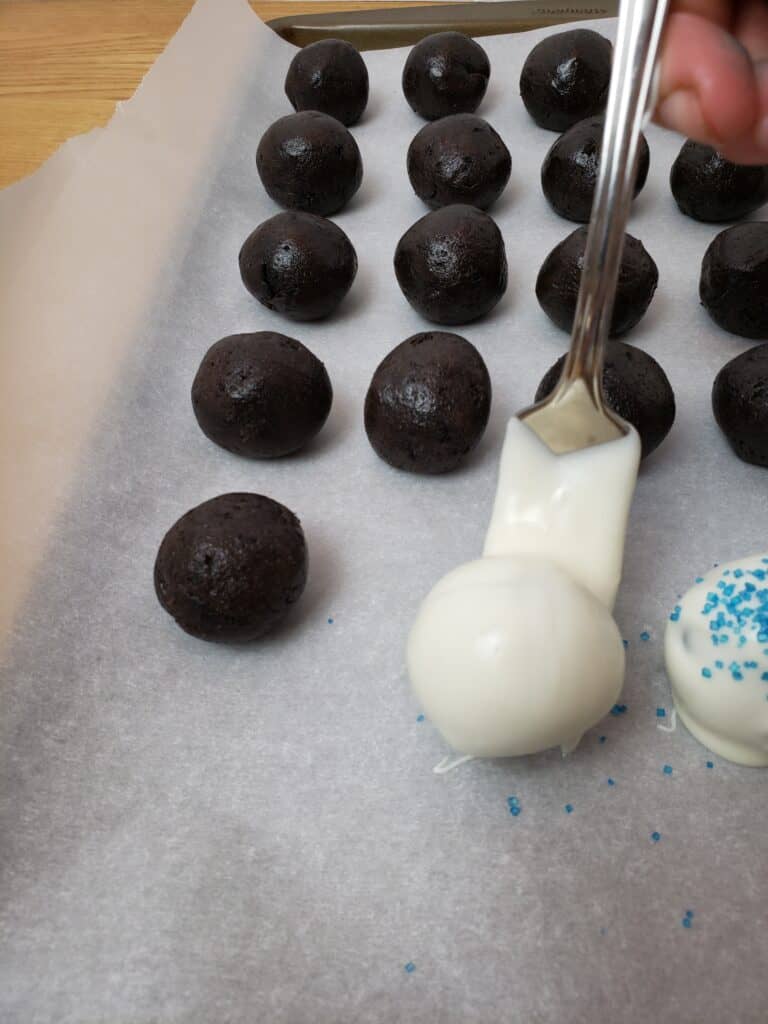 placing truffle onto parchment covered baking sheet next to others