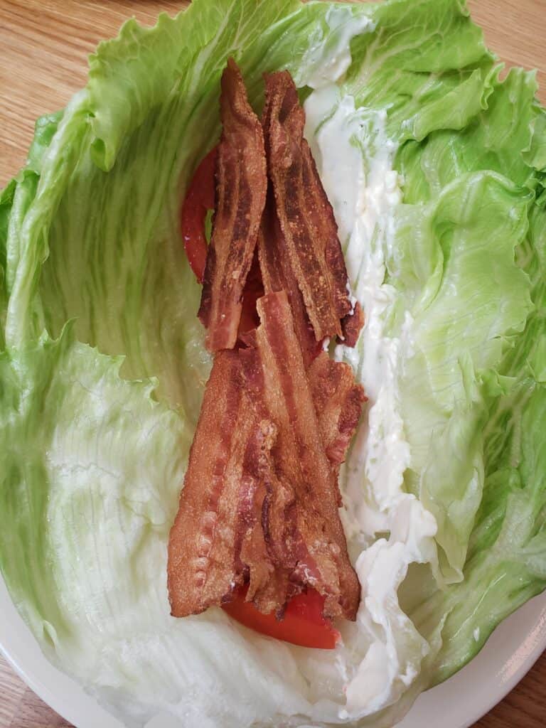 bacon on top of tomato in lettuce leaves