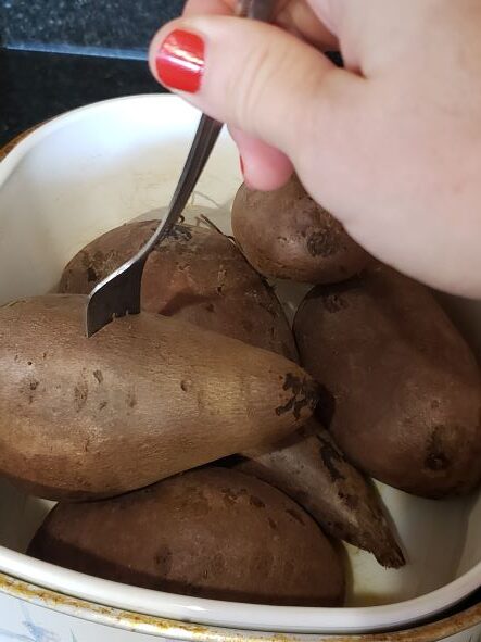 poking sweet potato with fork to test if done