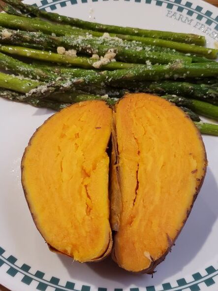sweet potato cut in half on plate with asparagus.