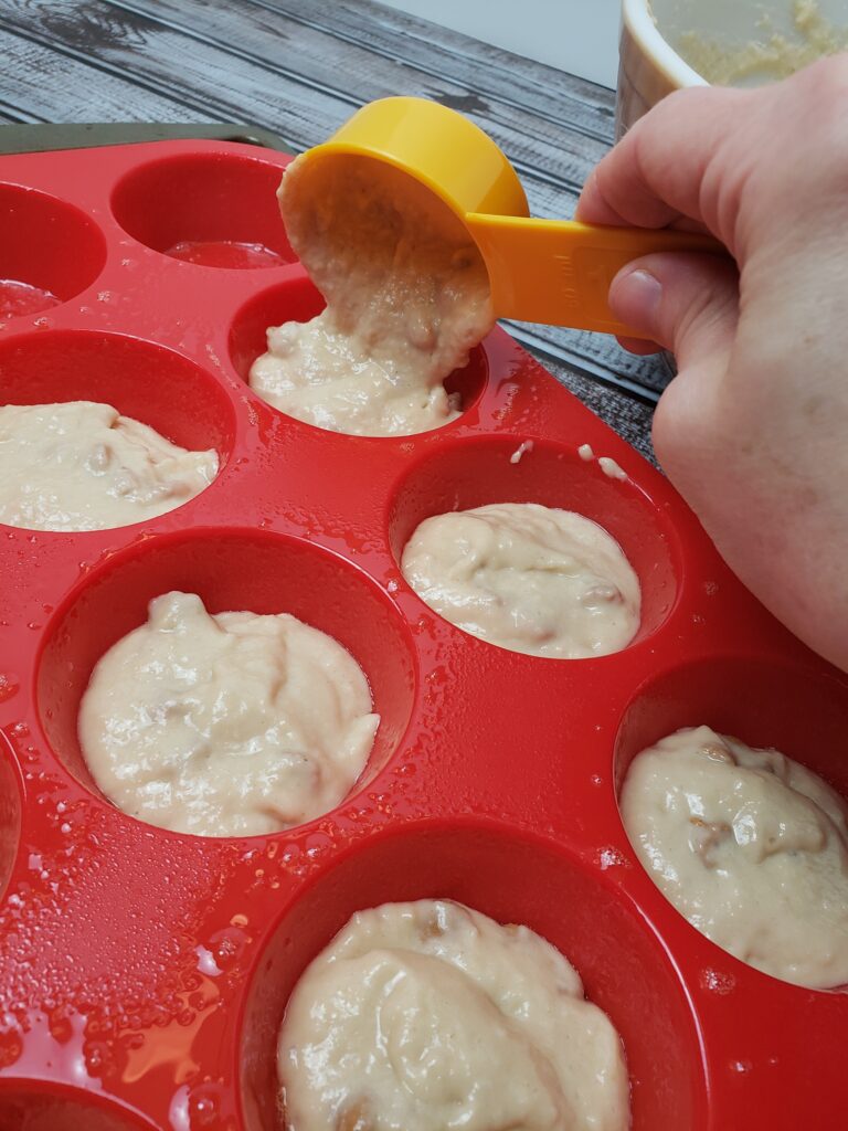 adding batter to muffin cups with scoop.