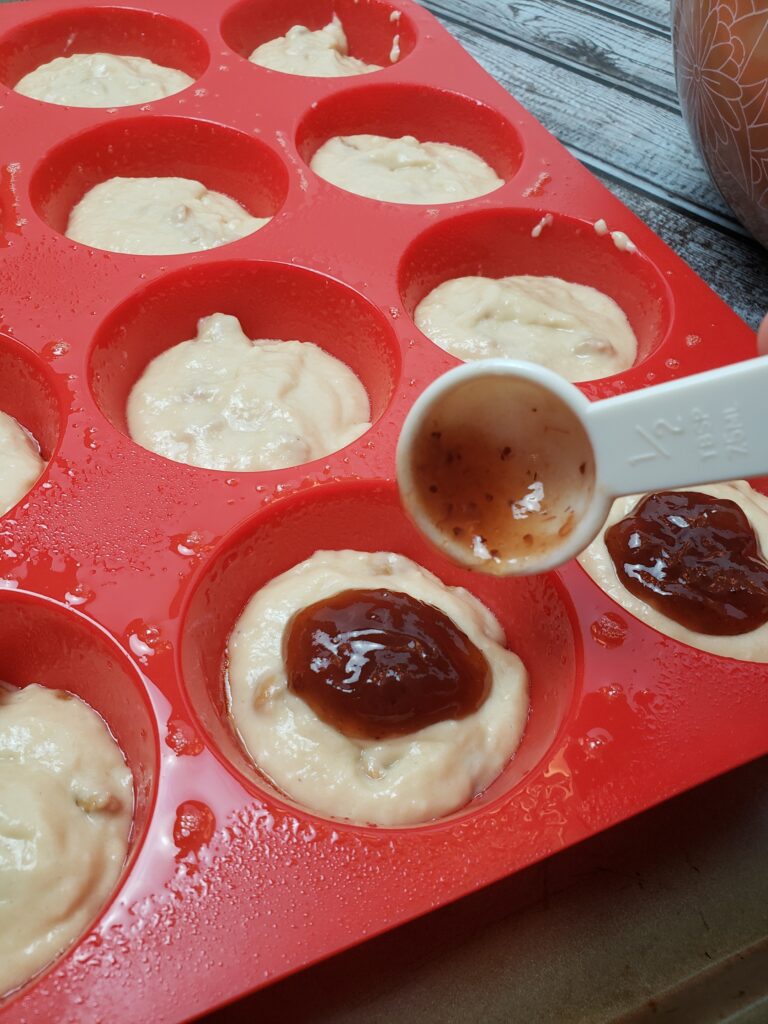 adding jelly to top of each muffin.