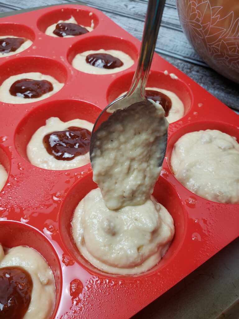 adding another spoonful of batter to top of each muffin.