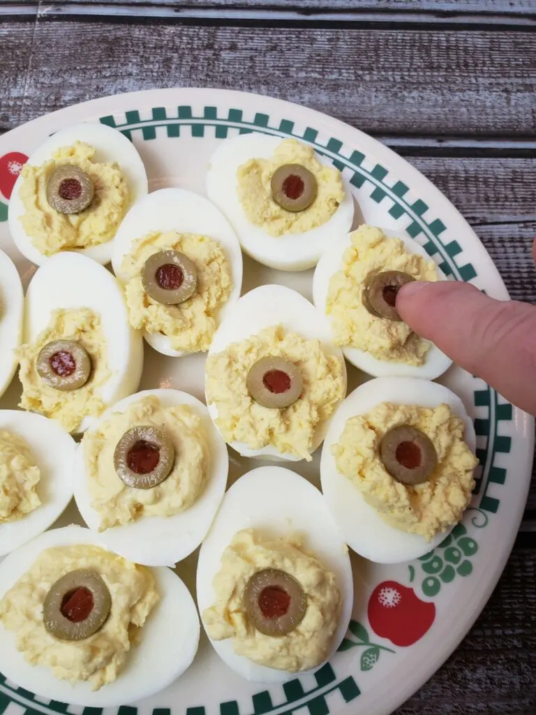 adding half of green olives to deviled eggs