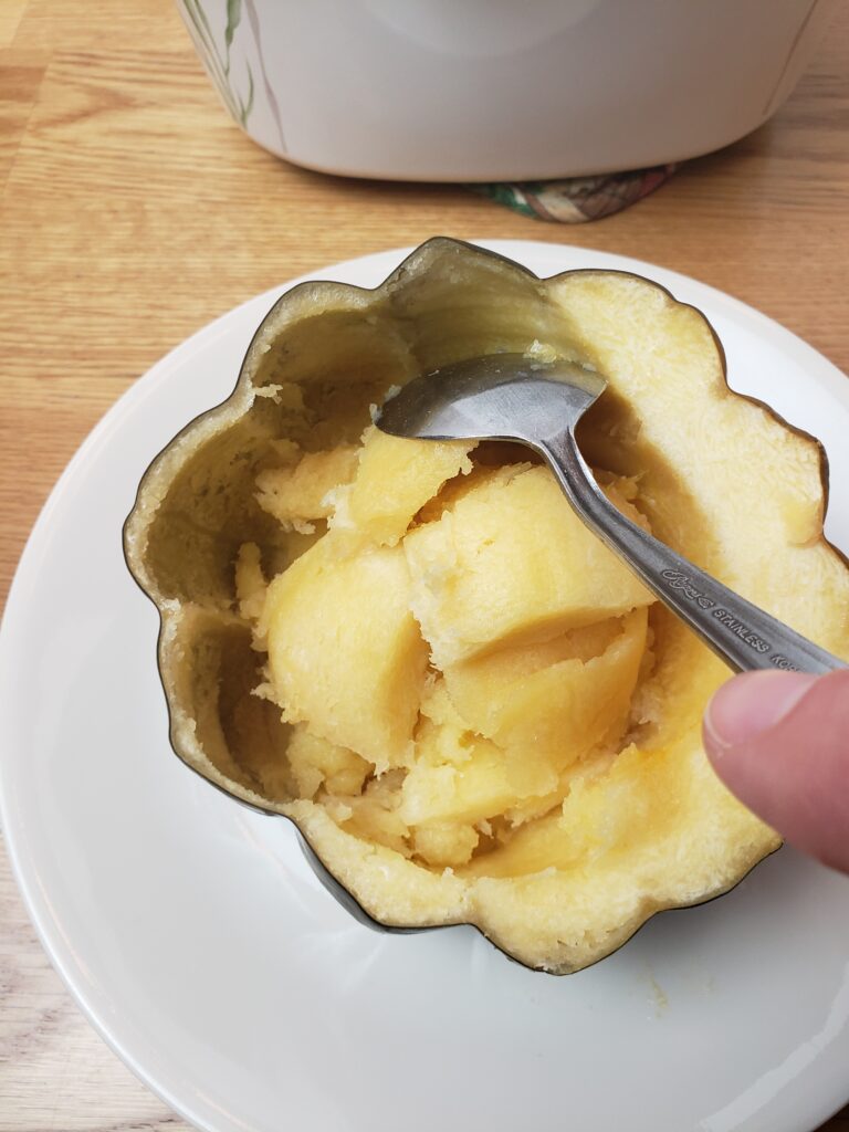 scooping out flesh of acorn squash with spoon.