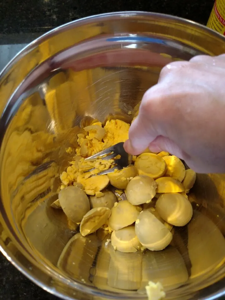 mashing egg yolks with fork in a bowl.