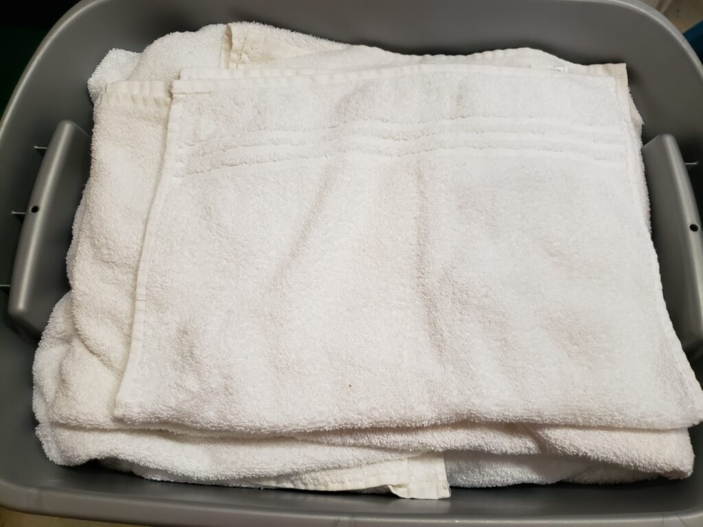 white towels folded in gray bins