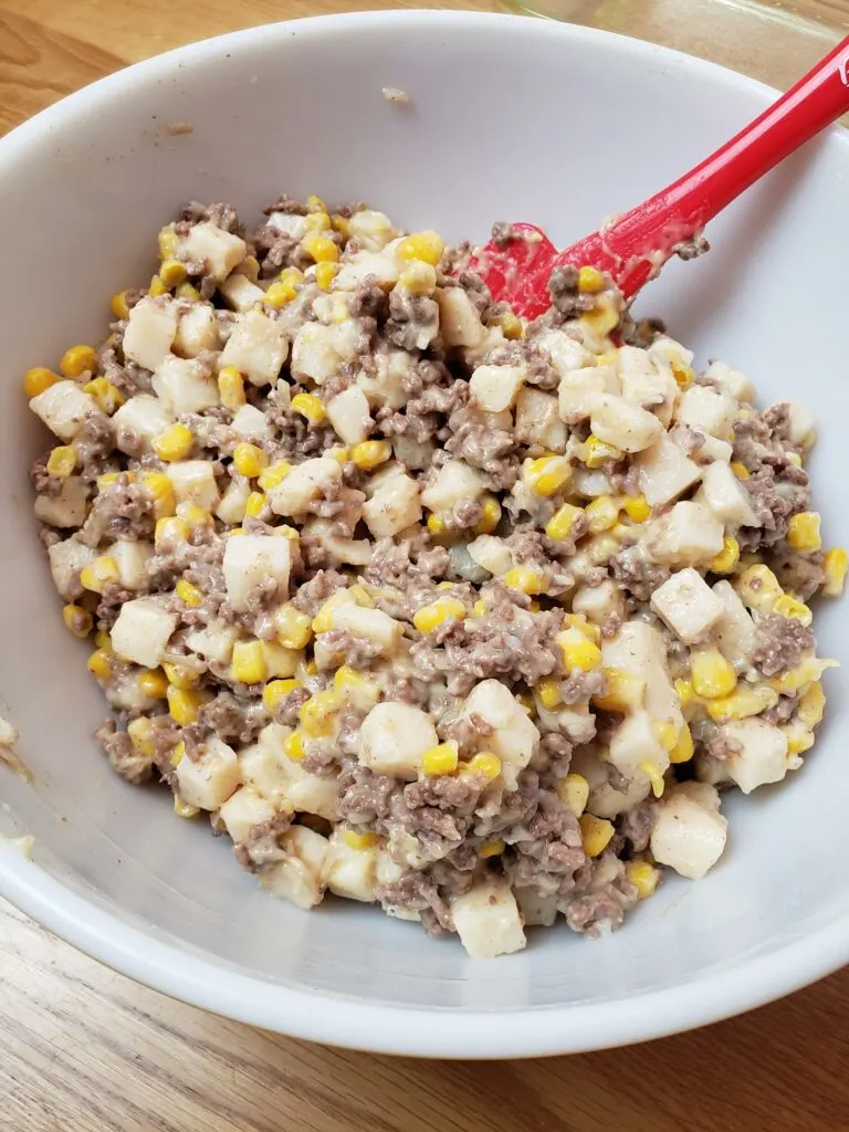 mixing potato, corn, beef and soup together