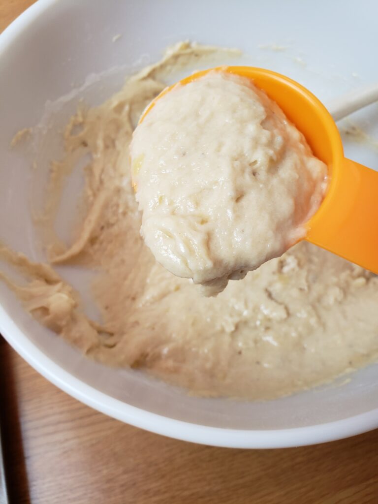 scooping muffin batter up with measuring cup