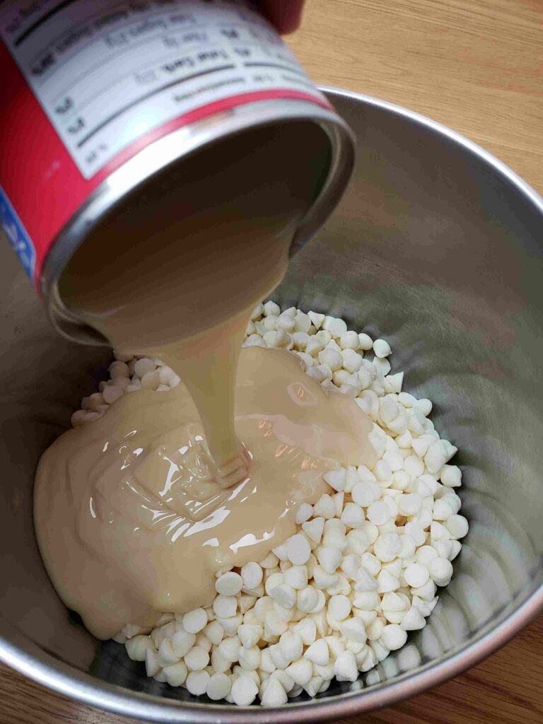adding white chips and condensed milk to saucepan