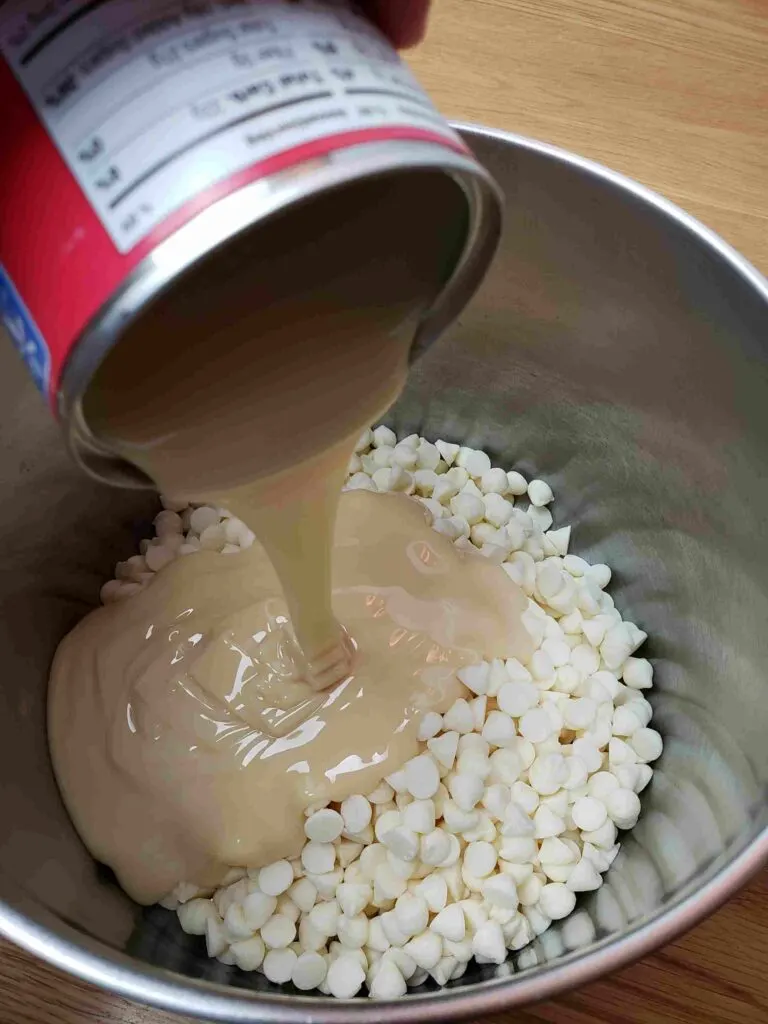 adding white chips and condensed milk to saucepan