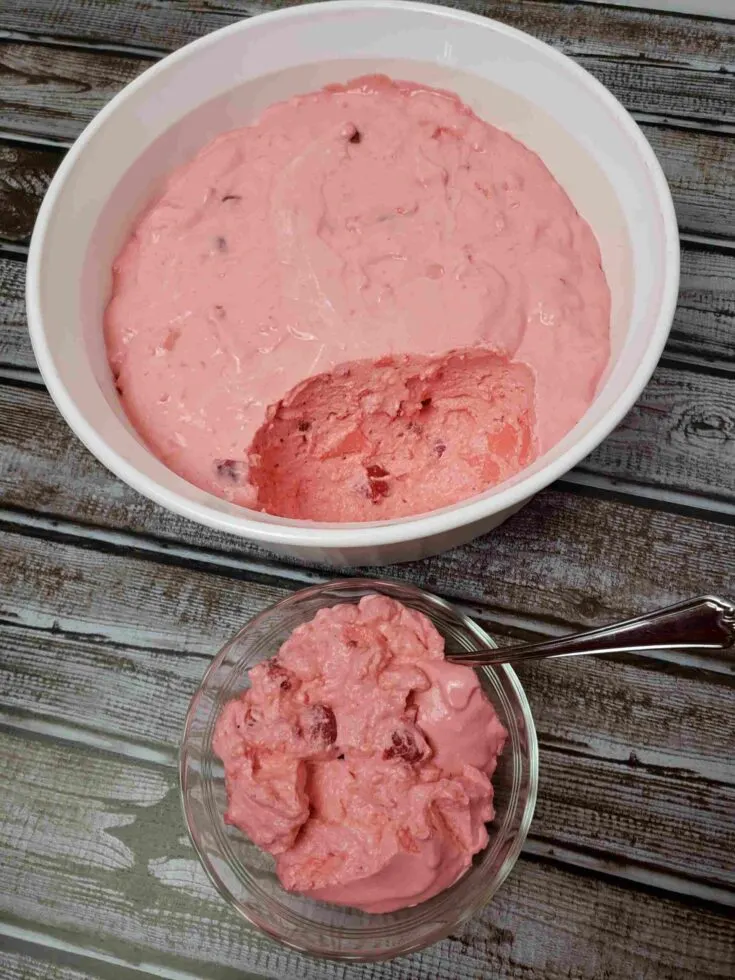 raspberry cherry jell-o in serving dish with one serving out in a small dish