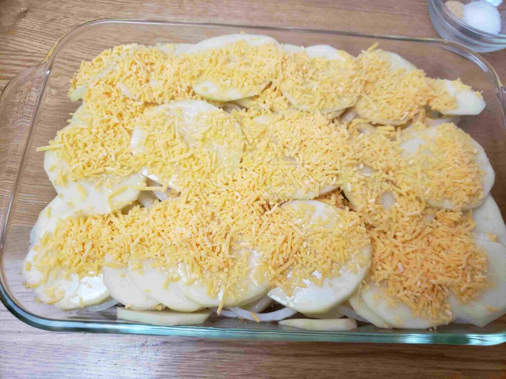 shredded cheese over potatoes and onions