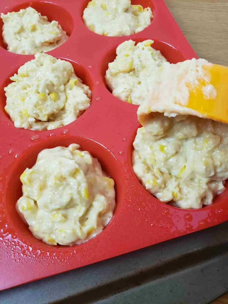 spooning muffin mix into muffin pan