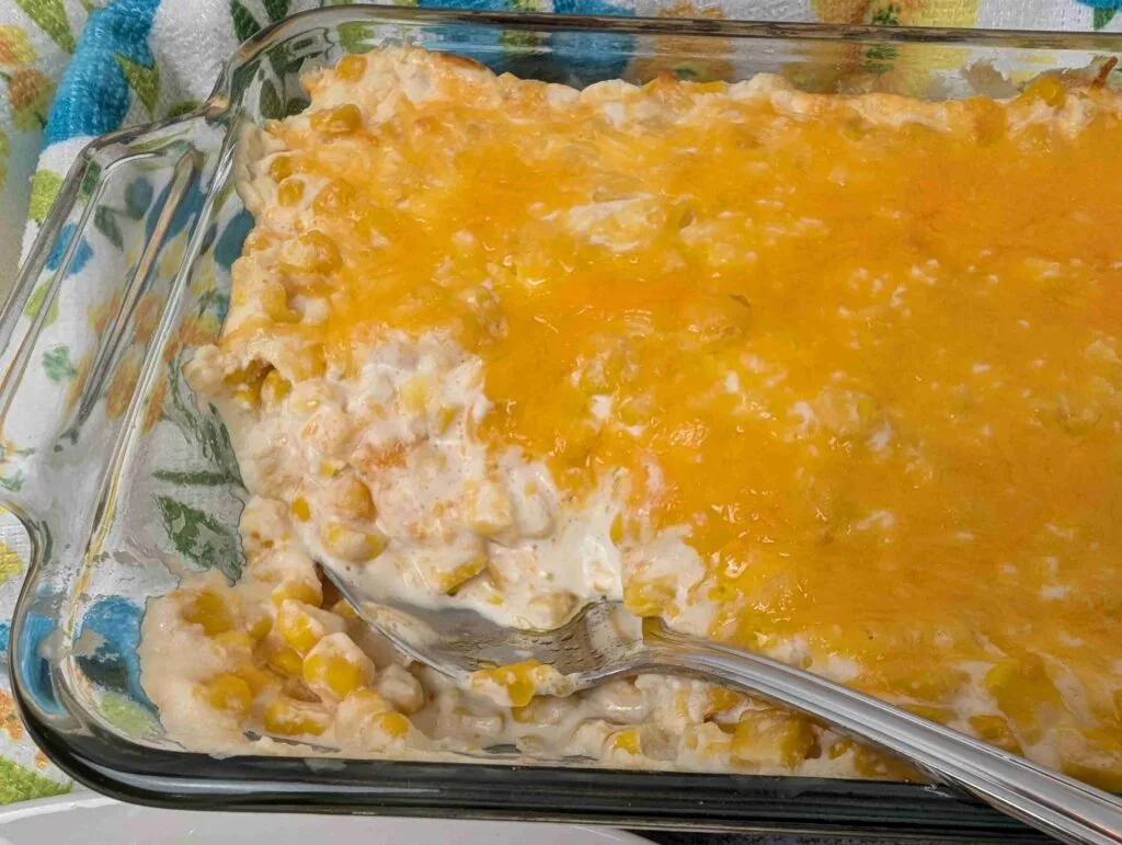 cheesy corn casserole with serving removed and spoon in the dish
