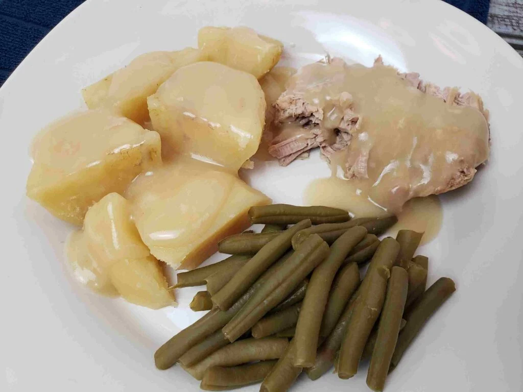 pork, potatoes and string beans on a white plate