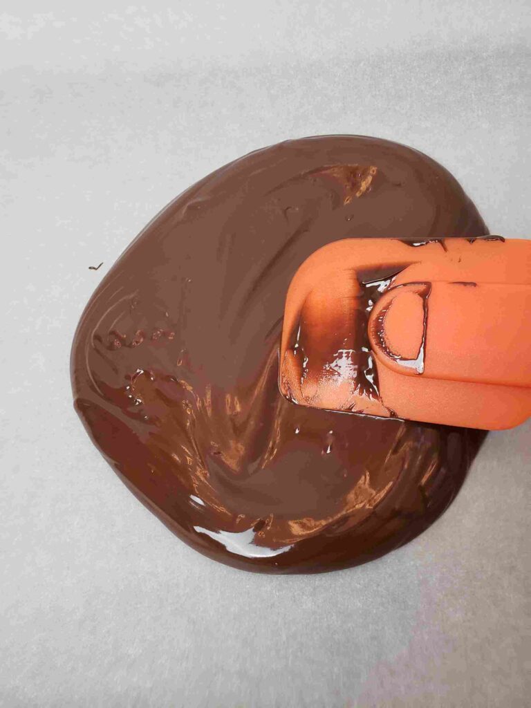 spreading chocolate onto parchment paper