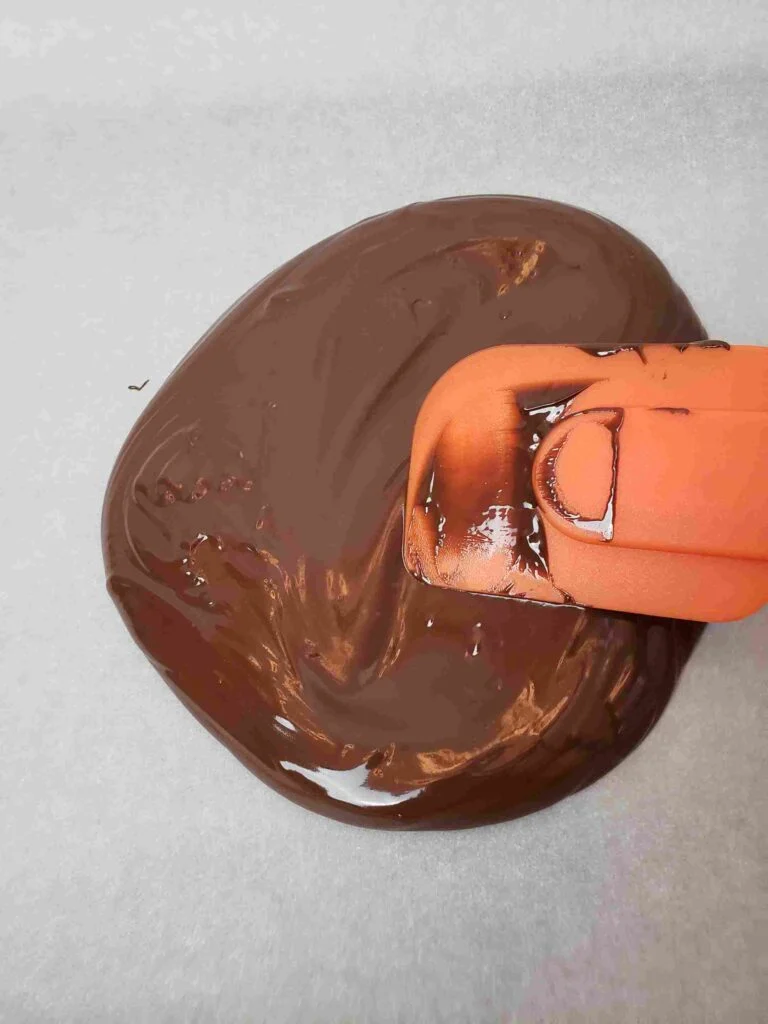 spreading chocolate onto parchment paper